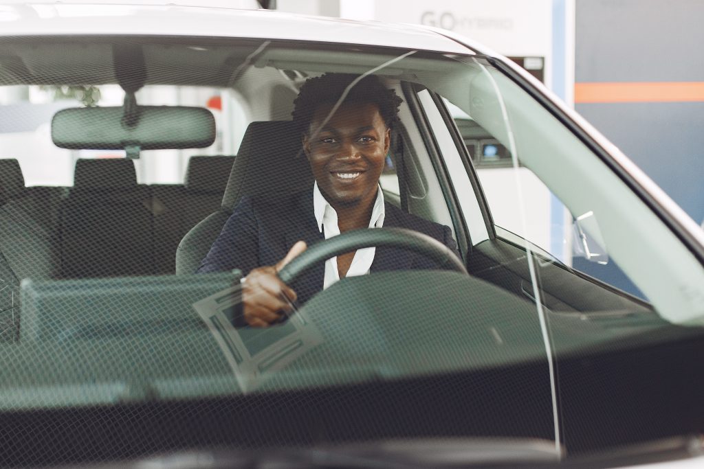 Man buying the car. Businessman in a car salon. Black male in a suit.
